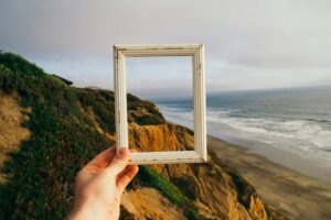 Hand holding a white frame against a landscape background