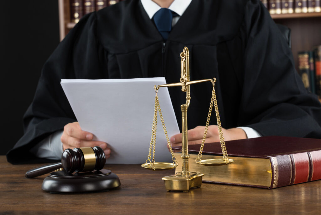 A judge sitting at his desk in a courtroom reviewing paperwork