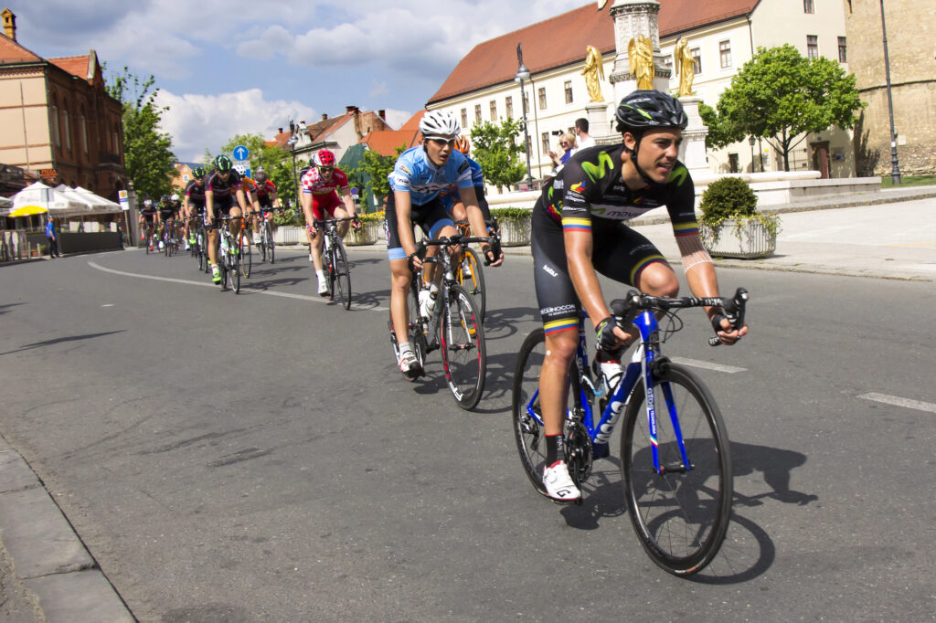 A peloton of bicycle riders travelling on a city road